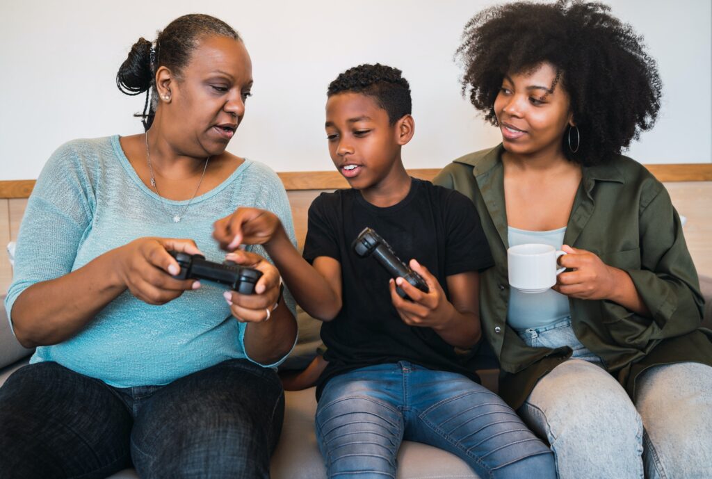 Child teaching grandmother and mother to play video games.